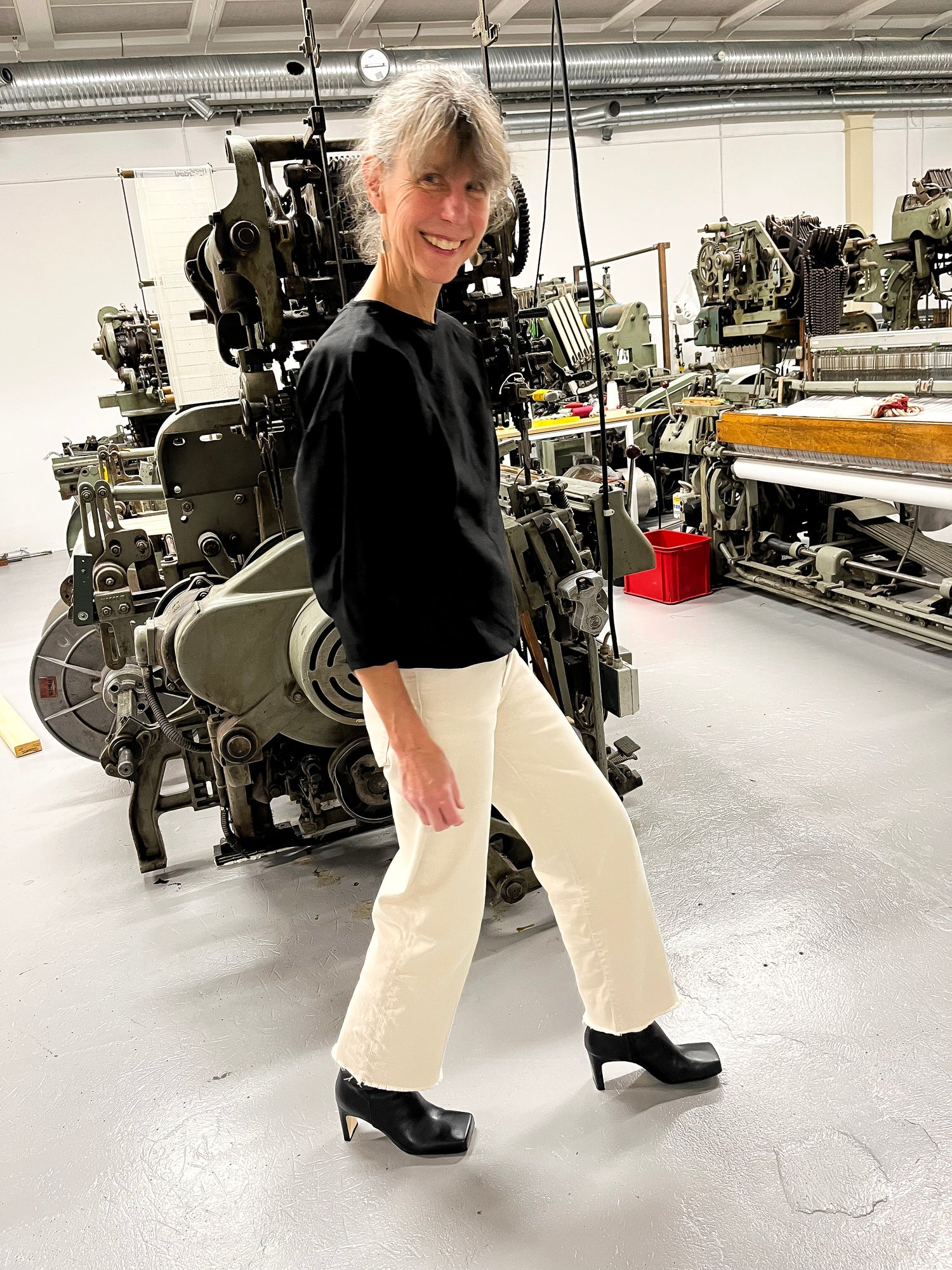 Delägaren av Björke Väveri står framför en av vävstolarna. Bär Kingfelt Footwears svarta skinnstövletter med fyrantig tå.