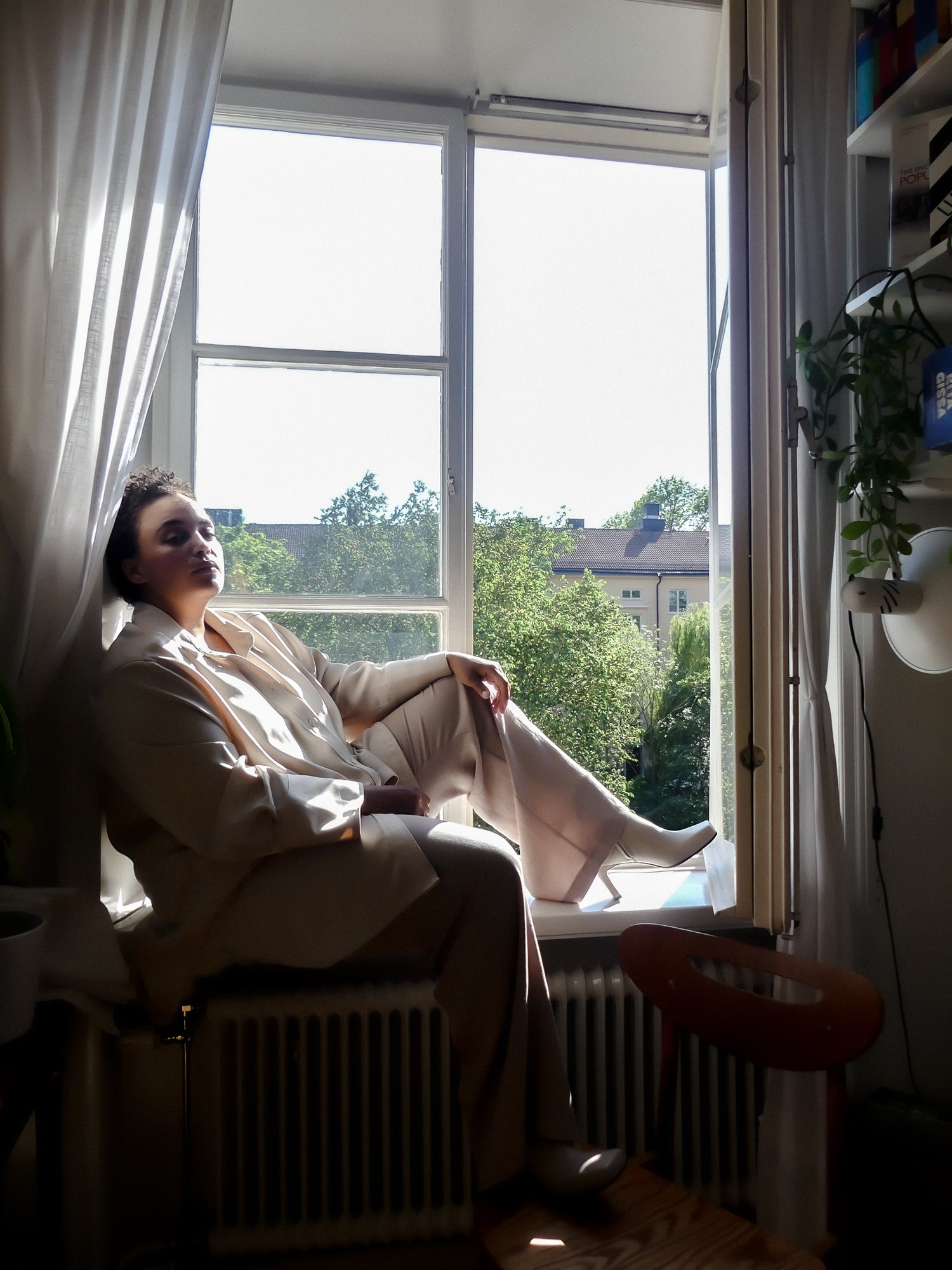 Regisör Klara sitter i ett fönster på söder i Stockholm. Bär beiga skinnstövletter i nappaskinn.
