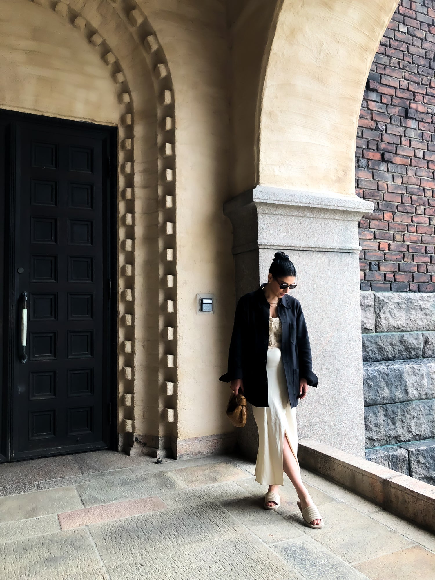 Likt en ballerina står ängelinvesteraren Gohar vid Stockholms stadshus med benen i kors något pointade medKINGFELT FOOTWEARs slip-in sandaler av nappaskinn. Beige med öppen tå och en mjuk vadderad ovandel och innerfoder av getskinn.