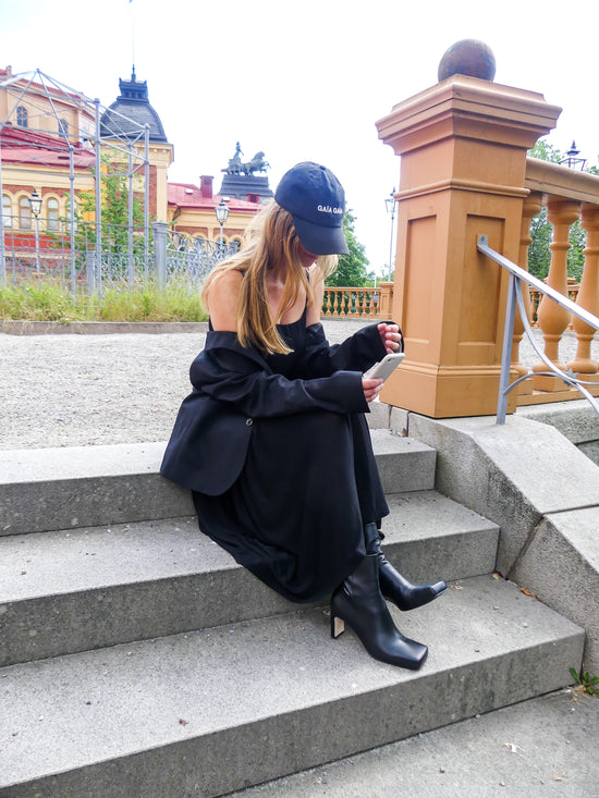Svarta fyrkantig tå skinnstövlleter från KINGFELT FOOTWEAR. Modell sitter på trapp och smsar med den ena skon helt i marken den vänstra lite tiltad upp. Handgjorda i Marche Italien.