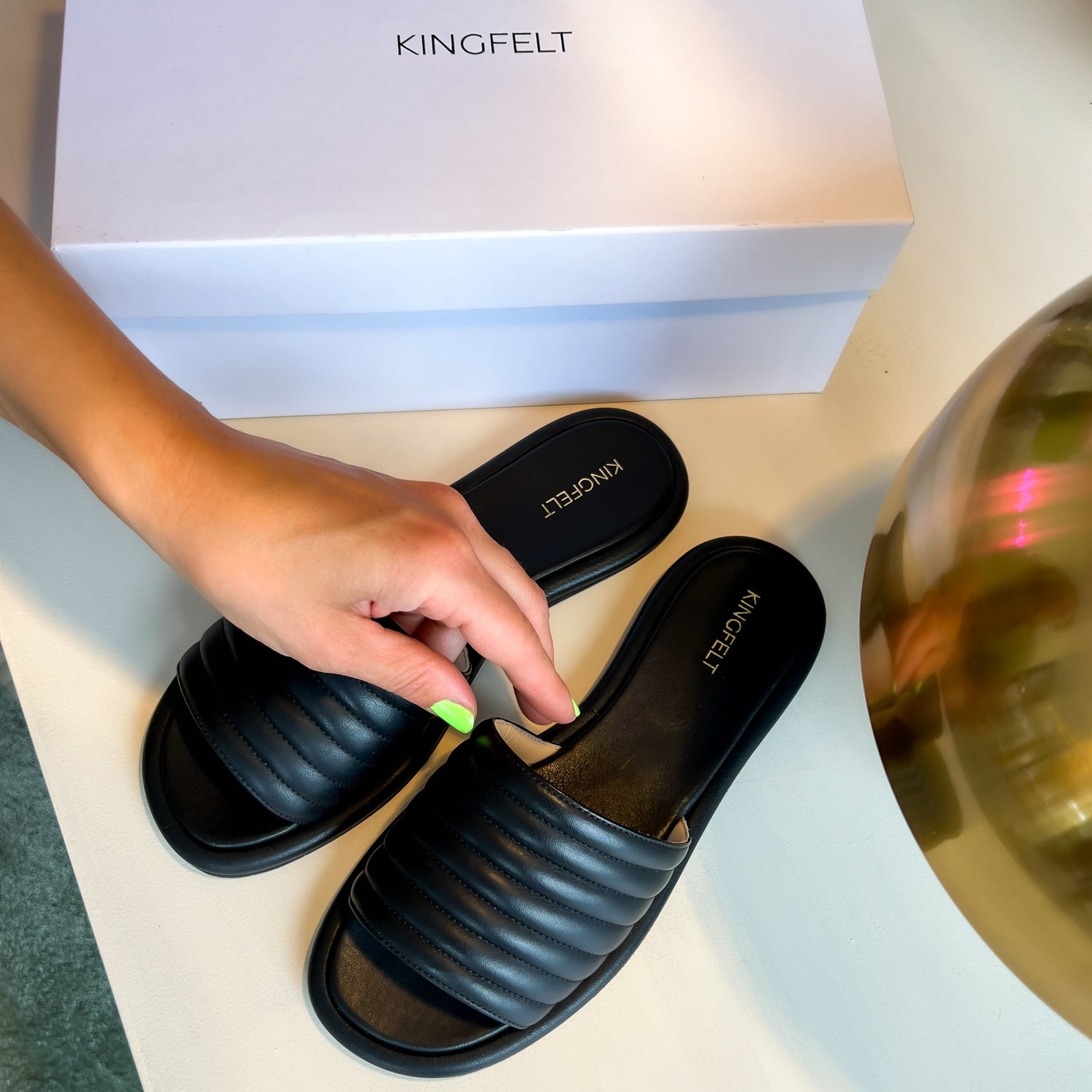 Svarta skinnsandaler som är handgjorda i Italien. Ligger på ett bord är fotade ovanifrån så man ser sulan och KINGFELT FOOTWEARs loga. 