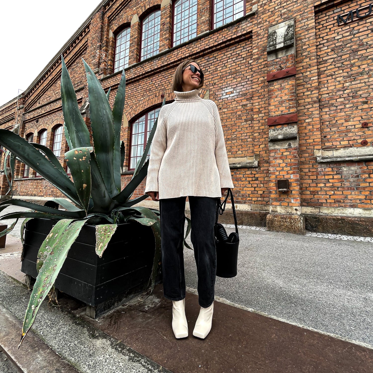 Beige skinnstövletter tillverkade av nappaskinn med en någon kantig tå. På kvinna med en tjock stickad tröja med polokrage och solglasögon, svarta denims och står med skorna framifrån så den snygga tån syns. Designade av KINGFELT FOOTWEAR tillverkade i Italien.