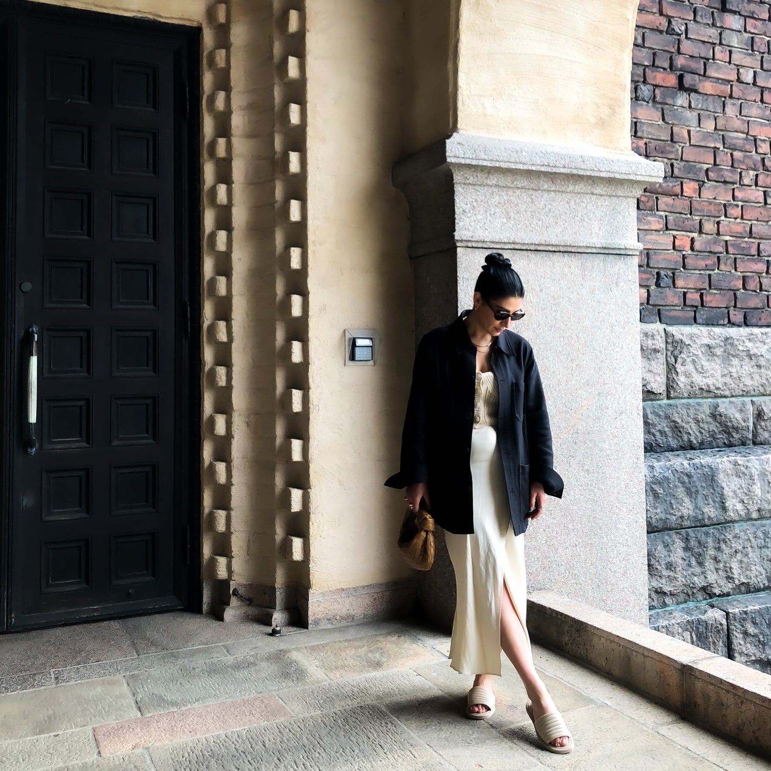 Gohar Avagyan vid stadshuset i Stockholm med KINGFELT FOOTWEARs beige slip-in sandaler av nappaskinn. En öppen tå sandal med vadderad padding på ovandelen och tillverkade i Italien. 